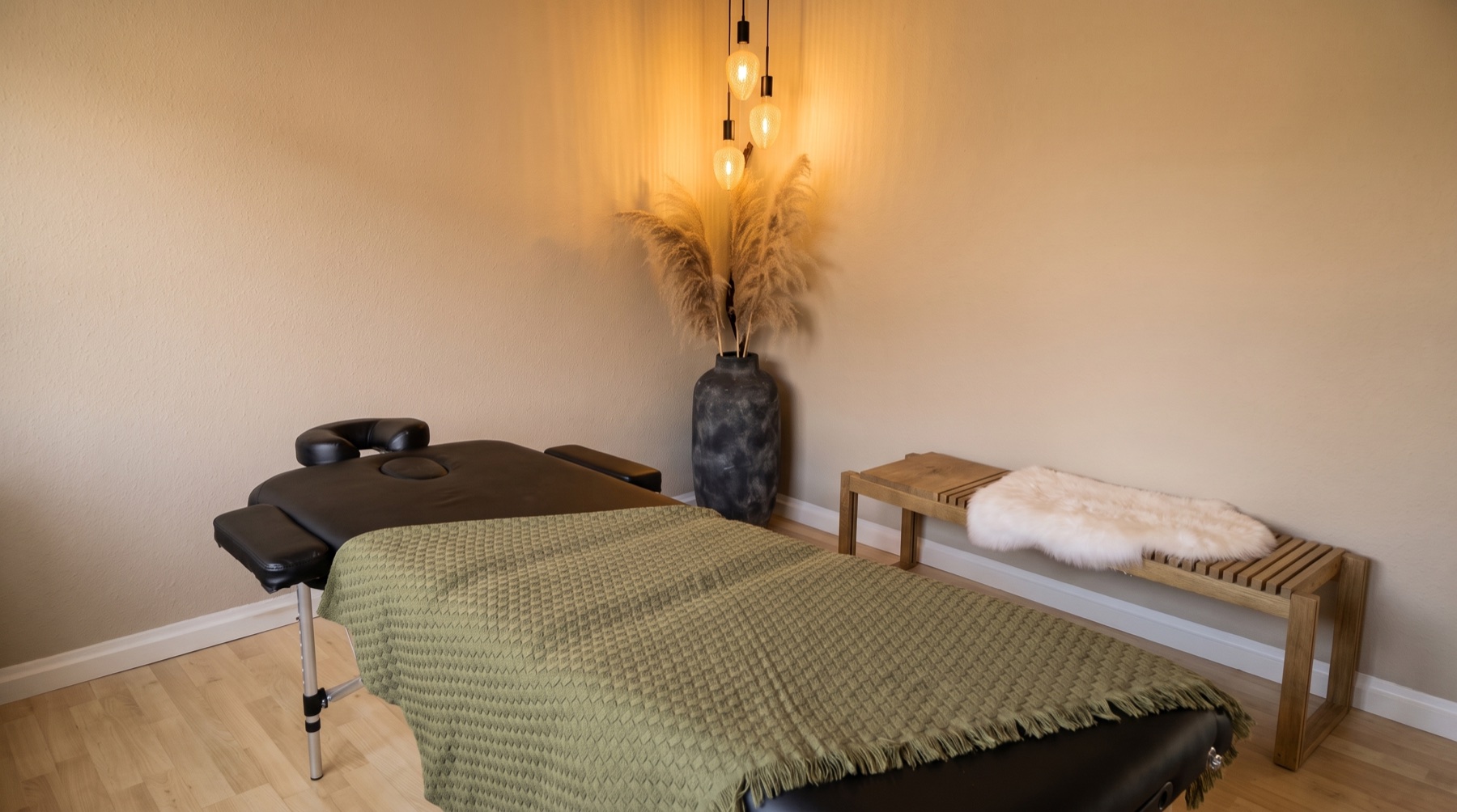 Roligt behandlingsrum hos Fysiurgisk Zone i Odder med massagebriks, sabelblomster og dæmpet belysning